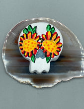 Load image into Gallery viewer, Heal emotionally and spiritually through art by honoring a loved one with a unique and beautiful Purple Spirit Piece Memorial Skull Art. Day Of The Dead Spirit Piece is an ideal addition to your ofrenda or altar that will provide a lasting tribute. These handcrafted polymer clay skull figurines are adorned with hand-painted bright yellow floral designs for the eyes. H 1 1/2” x W 1 1/2” x D 3/4”