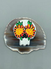 Load image into Gallery viewer, Heal emotionally and spiritually through art by honoring a loved one with a unique and beautiful Purple Spirit Piece Memorial Skull Art. Day Of The Dead Spirit Piece is an ideal addition to your ofrenda or altar that will provide a lasting tribute. These handcrafted polymer clay skull figurines are adorned with hand-painted bright yellow floral designs for the eyes. H 1 1/2” x W 1 1/2” x D 3/4”