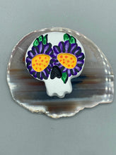Load image into Gallery viewer, Heal emotionally and spiritually through art by honoring a loved one with a unique and beautiful Purple Spirit Piece Memorial Skull Art. Day Of The Dead Spirit Piece is an ideal addition to your ofrenda or altar that will provide a lasting tribute. These handcrafted polymer clay skull figurines are adorned with hand-painted dark purple floral designs for the eyes. H 1 1/2” x W 1 1/2” x D 3/4”