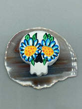 Load image into Gallery viewer, Heal emotionally and spiritually through art by honoring a loved one with a unique and beautiful Purple Spirit Piece Memorial Skull Art. Day Of The Dead Spirit Piece is an ideal addition to your ofrenda or altar that will provide a lasting tribute. These handcrafted polymer clay skull figurines are adorned with hand-painted light blue floral designs for the eyes. H 1 1/2” x W 1 1/2” x D 3/4”