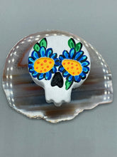 Load image into Gallery viewer, Heal emotionally and spiritually through art by honoring a loved one with a unique and beautiful Purple Spirit Piece Memorial Skull Art. Day Of The Dead Spirit Piece is an ideal addition to your ofrenda or altar that will provide a lasting tribute. These handcrafted polymer clay skull figurines are adorned with hand-painted dark blue floral designs for the eyes. H 1 1/2” x W 1 1/2” x D 3/4”