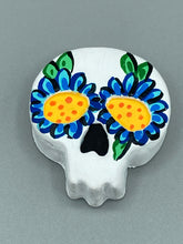Load image into Gallery viewer, Heal emotionally and spiritually through art by honoring a loved one with a unique and beautiful Purple Spirit Piece Memorial Skull Art. Day Of The Dead Spirit Piece is an ideal addition to your ofrenda or altar that will provide a lasting tribute. These handcrafted polymer clay skull figurines are adorned with hand-painted dark blue floral designs for the eyes. H 1 1/2” x W 1 1/2” x D 3/4”