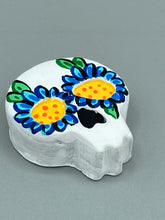 Load image into Gallery viewer, Heal emotionally and spiritually through art by honoring a loved one with a unique and beautiful Purple Spirit Piece Memorial Skull Art. Day Of The Dead Spirit Piece is an ideal addition to your ofrenda or altar that will provide a lasting tribute. These handcrafted polymer clay skull figurines are adorned with hand-painted dark blue floral designs for the eyes. H 1 1/2” x W 1 1/2” x D 3/4”