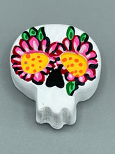 Load image into Gallery viewer, Heal emotionally and spiritually through art by honoring a loved one with a unique and beautiful Purple Spirit Piece Memorial Skull Art. Day Of The Dead Spirit Piece is an ideal addition to your ofrenda or altar that will provide a lasting tribute. These handcrafted polymer clay skull figurines are adorned with hand-painted pink floral designs for the eyes. H 1 1/2” x W 1 1/2” x D 3/4”
