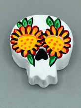 Load image into Gallery viewer, Heal emotionally and spiritually through art by honoring a loved one with a unique and beautiful Purple Spirit Piece Memorial Skull Art. Day Of The Dead Spirit Piece is an ideal addition to your ofrenda or altar that will provide a lasting tribute. These handcrafted polymer clay skull figurines are adorned with hand-painted bright orange floral designs for the eyes. H 1 1/2” x W 1 1/2” x D 3/4”