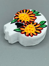 Load image into Gallery viewer, Heal emotionally and spiritually through art by honoring a loved one with a unique and beautiful Purple Spirit Piece Memorial Skull Art. Day Of The Dead Spirit Piece is an ideal addition to your ofrenda or altar that will provide a lasting tribute. These handcrafted polymer clay skull figurines are adorned with hand-painted bright orange floral designs for the eyes. H 1 1/2” x W 1 1/2” x D 3/4”