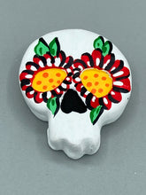 Load image into Gallery viewer, Heal emotionally and spiritually through art by honoring a loved one with a unique and beautiful Purple Spirit Piece Memorial Skull Art. Day Of The Dead Spirit Piece is an ideal addition to your ofrenda or altar that will provide a lasting tribute. These handcrafted polymer clay skull figurines are adorned with hand-painted red floral designs for the eyes. H 1 1/2” x W 1 1/2” x D 3/4”