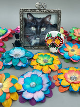 Load image into Gallery viewer, Heal emotionally and spiritually through art by honoring a loved one with a unique and beautiful Purple Spirit Piece Memorial Skull Art. Day Of The Dead Spirit Piece is an ideal addition to your ofrenda or altar that will provide a lasting tribute. These handcrafted polymer clay skull figurines are adorned with hand-painted dark floral designs for the eyes. H 1 1/2” x W 1 1/2” x D 3/4”