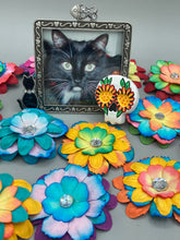 Load image into Gallery viewer, Heal emotionally and spiritually through art by honoring a loved one with a unique and beautiful Purple Spirit Piece Memorial Skull Art. Day Of The Dead Spirit Piece is an ideal addition to your ofrenda or altar that will provide a lasting tribute. These handcrafted polymer clay skull figurines are adorned with hand-painted dark floral designs for the eyes. H 1 1/2” x W 1 1/2” x D 3/4”