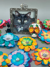 Load image into Gallery viewer, Heal emotionally and spiritually through art by honoring a loved one with a unique and beautiful Purple Spirit Piece Memorial Skull Art. Day Of The Dead Spirit Piece is an ideal addition to your ofrenda or altar that will provide a lasting tribute. These handcrafted polymer clay skull figurines are adorned with hand-painted dark floral designs for the eyes. H 1 1/2” x W 1 1/2” x D 3/4”