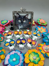 Load image into Gallery viewer, Heal emotionally and spiritually through art by honoring a loved one with a unique and beautiful Purple Spirit Piece Memorial Skull Art. Day Of The Dead Spirit Piece is an ideal addition to your ofrenda or altar that will provide a lasting tribute. These handcrafted polymer clay skull figurines are adorned with hand-painted dark floral designs for the eyes. H 1 1/2” x W 1 1/2” x D 3/4”