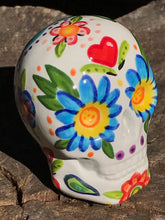 Load image into Gallery viewer, This hand-painted, mini ceramic sugar skull art piece is inspired by peacock feathers, perfect colorful artwork for Dia de Los Muertos. The intricate design captures the beauty of peacock feathers bring a unique and beautiful piece to your ofrenda and celebrate your loved ones in style. Measurements: H 2 3/4” x W 2” x D 2”