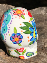 Load image into Gallery viewer, This hand-painted, mini ceramic sugar skull art piece is inspired by peacock feathers, perfect colorful artwork for Dia de Los Muertos. The intricate design captures the beauty of peacock feathers bring a unique and beautiful piece to your ofrenda and celebrate your loved ones in style. Measurements: H 2 3/4” x W 2” x D 2”