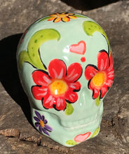 Load image into Gallery viewer, This Mini Light Green Dia De Los Muertos Hand Painted Ceramic Sugar Skull is an artistic work of art inspired by Nature. Featuring a vibrant red and white poppy flower, this mini Day of the Dead Calavera brings a touch of color and spirit to any altars or gothic art collections. Enhance your ofrenda with this beautiful Calaca De Ofrenda. Measurements: H 2 3/4” x W 2” x D 2”