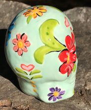 Load image into Gallery viewer, This Mini Light Green Dia De Los Muertos Hand Painted Ceramic Sugar Skull is an artistic work of art inspired by Nature. Featuring a vibrant red and white poppy flower, this mini Day of the Dead Calavera brings a touch of color and spirit to any altars or gothic art collections. Enhance your ofrenda with this beautiful Calaca De Ofrenda. Measurements: H 2 3/4” x W 2” x D 2”