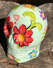 Load image into Gallery viewer, This Mini Light Green Dia De Los Muertos Hand Painted Ceramic Sugar Skull is an artistic work of art inspired by Nature. Featuring a vibrant red and white poppy flower, this mini Day of the Dead Calavera brings a touch of color and spirit to any altars or gothic art collections. Enhance your ofrenda with this beautiful Calaca De Ofrenda. Measurements: H 2 3/4” x W 2” x D 2”