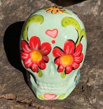 Load image into Gallery viewer, This Mini Light Green Dia De Los Muertos Hand Painted Ceramic Sugar Skull is an artistic work of art inspired by Nature. Featuring a vibrant red and white poppy flower, this mini Day of the Dead Calavera brings a touch of color and spirit to any altars or gothic art collections. Enhance your ofrenda with this beautiful Calaca De Ofrenda. Measurements: H 2 3/4” x W 2” x D 2”