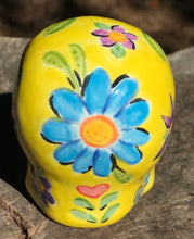 Load image into Gallery viewer, This ceramic skull statuette is a stunning piece of art inspired by nature. Its vibrant yellow hue is decorated with multi-color floral motifs, hearts, leaves and colorful accents, creating a beautiful piece of hand-painted, Day of the Dead-themed art. Measurements: H 2 3/4” x W 2” x D 2”