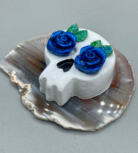 Load image into Gallery viewer, Cremation memorial art, such as Day of the Dead Spirit Pieces, provide a unique way to keep a loved one close to your heart. Handcrafted with care, each piece of artwork is specially tailored to the individual, providing a lasting reminder of those who are dearly missed. On altars and ofrendas, these pieces make a beautiful addition. Composed with meticulous attention to detail, these mini polymer clay skulls feature hand sculpted dark blue roses and leaves. H 1 1/2” x W 1 1/2” x D 3/4”