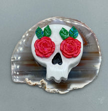 Load image into Gallery viewer, Cremation memorial art, such as Day of the Dead Spirit Pieces, provide a unique way to keep a loved one close to your heart. Handcrafted with care, each piece of artwork is specially tailored to the individual, providing a lasting reminder of those who are dearly missed. On altars and ofrendas, these pieces make a beautiful addition. Composed with meticulous attention to detail, these mini polymer clay skulls feature hand sculpted bright pink roses and leaves. H 1 1/2” x W 1 1/2” x D 3/4”