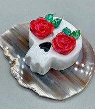 Load image into Gallery viewer, Cremation memorial art, such as Day of the Dead Spirit Pieces, provide a unique way to keep a loved one close to your heart. Handcrafted with care, each piece of artwork is specially tailored to the individual, providing a lasting reminder of those who are dearly missed. On altars and ofrendas, these pieces make a beautiful addition. Composed with meticulous attention to detail, these mini polymer clay skulls feature hand sculpted bright pink roses and leaves. H 1 1/2” x W 1 1/2” x D 3/4”