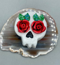 Load image into Gallery viewer, Cremation memorial art, such as Day of the Dead Spirit Pieces, provide a unique way to keep a loved one close to your heart. Handcrafted with care, each piece of artwork is specially tailored to the individual, providing a lasting reminder of those who are dearly missed. On altars and ofrendas, these pieces make a beautiful addition. Composed with meticulous attention to detail, these mini polymer clay skulls feature hand sculpted bright red roses and leaves. H 1 1/2” x W 1 1/2” x D 3/4”