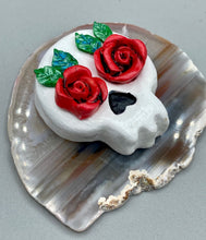 Load image into Gallery viewer, Cremation memorial art, such as Day of the Dead Spirit Pieces, provide a unique way to keep a loved one close to your heart. Handcrafted with care, each piece of artwork is specially tailored to the individual, providing a lasting reminder of those who are dearly missed. On altars and ofrendas, these pieces make a beautiful addition. Composed with meticulous attention to detail, these mini polymer clay skulls feature hand sculpted bright red roses and leaves. H 1 1/2” x W 1 1/2” x D 3/4”
