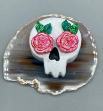 Load image into Gallery viewer, Cremation memorial art, such as Day of the Dead Spirit Pieces, provide a unique way to keep a loved one close to your heart. Handcrafted with care, each piece of artwork is specially tailored to the individual, providing a lasting reminder of those who are dearly missed. On altars and ofrendas, these pieces make a beautiful addition. Composed with meticulous attention to detail, these mini polymer clay skulls feature hand sculpted light pink roses and leaves. H 1 1/2” x W 1 1/2” x D 3/4”