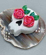 Load image into Gallery viewer, Cremation memorial art, such as Day of the Dead Spirit Pieces, provide a unique way to keep a loved one close to your heart. Handcrafted with care, each piece of artwork is specially tailored to the individual, providing a lasting reminder of those who are dearly missed. On altars and ofrendas, these pieces make a beautiful addition. Composed with meticulous attention to detail, these mini polymer clay skulls feature hand sculpted pink roses and leaves. H 1 1/2” x W 1 1/2” x D 3/4”