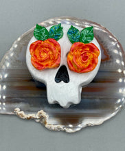 Load image into Gallery viewer, Cremation memorial art, such as Day of the Dead Spirit Pieces, provide a unique way to keep a loved one close to your heart. Handcrafted with care, each piece of artwork is specially tailored to the individual, providing a lasting reminder of those who are dearly missed. On altars and ofrendas, these pieces make a beautiful addition. Composed with meticulous attention to detail, these mini polymer clay skulls feature hand sculpted bright orange/yellow roses and leaves. H 1 1/2” x W 1 1/2” x D 3/4”