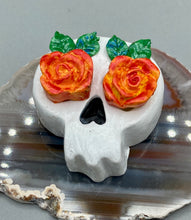 Load image into Gallery viewer, Cremation memorial art, such as Day of the Dead Spirit Pieces, provide a unique way to keep a loved one close to your heart. Handcrafted with care, each piece of artwork is specially tailored to the individual, providing a lasting reminder of those who are dearly missed. On altars and ofrendas, these pieces make a beautiful addition. Composed with meticulous attention to detail, these mini polymer clay skulls feature hand sculpted bright orange/yellow roses and leaves. H 1 1/2” x W 1 1/2” x D 3/4”