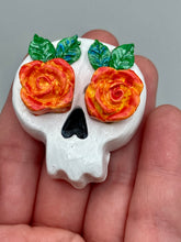 Load image into Gallery viewer, Cremation memorial art, such as Day of the Dead Spirit Pieces, provide a unique way to keep a loved one close to your heart. Handcrafted with care, each piece of artwork is specially tailored to the individual, providing a lasting reminder of those who are dearly missed. On altars and ofrendas, these pieces make a beautiful addition. Composed with meticulous attention to detail, these mini polymer clay skulls feature hand sculpted bright orange/yellow roses and leaves. H 1 1/2” x W 1 1/2” x D 3/4”