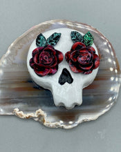 Load image into Gallery viewer, Cremation memorial art, such as Day of the Dead Spirit Pieces, provide a unique way to keep a loved one close to your heart. Handcrafted with care, each piece of artwork is specially tailored to the individual, providing a lasting reminder of those who are dearly missed. On altars and ofrendas, these pieces make a beautiful addition. Composed with meticulous attention to detail, these mini polymer clay skulls feature hand sculpted dark red roses and leaves. H 1 1/2” x W 1 1/2” x D 3/4”