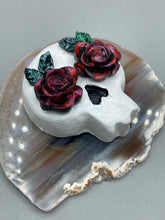 Load image into Gallery viewer, Cremation memorial art, such as Day of the Dead Spirit Pieces, provide a unique way to keep a loved one close to your heart. Handcrafted with care, each piece of artwork is specially tailored to the individual, providing a lasting reminder of those who are dearly missed. On altars and ofrendas, these pieces make a beautiful addition. Composed with meticulous attention to detail, these mini polymer clay skulls feature hand sculpted dark red roses and leaves. H 1 1/2” x W 1 1/2” x D 3/4”