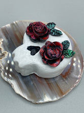 Load image into Gallery viewer, Cremation memorial art, such as Day of the Dead Spirit Pieces, provide a unique way to keep a loved one close to your heart. Handcrafted with care, each piece of artwork is specially tailored to the individual, providing a lasting reminder of those who are dearly missed. On altars and ofrendas, these pieces make a beautiful addition. Composed with meticulous attention to detail, these mini polymer clay skulls feature hand sculpted dark red roses and leaves. H 1 1/2” x W 1 1/2” x D 3/4”