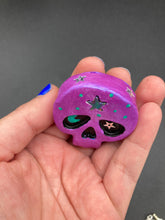 Load image into Gallery viewer, Inspired by nature, this skull statuette is full of shimmery metallic, and vibrant colors and intricate details. The metallic violet color reminds me of sundown, when the sky is illuminating from blue to purple to black. I painted a moon and stars with a teal/green paint to really create a beautiful contrast against the violet color. The forehead of the skully has a beautiful rainbow hematite star bead.