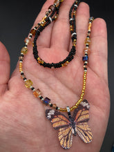Load image into Gallery viewer, Sterling silver butterfly pendant is molded from a basil leaf and is painted in strikingly bright orange and black. The first two strands contain two-hole black and silver beads to retain a more "collar" shape. They are primarily black beads with larger orange beads. The third and slightly longer strand has bright gold and orange square shaped glass beads along the black beads to compliment the monarch butterfly wings. Perfect for your summer look! Necklace is 14” adjustable up to 18" - pendant is 1”