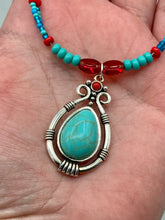 Load image into Gallery viewer, This captivating Southwestern style necklace features a two-strand design of bold and vibrant turquoise and red glass beads. At the center, a bright turquoise pendant is framed in a distinctive design. Measurements: Necklace is 16 1/2 ” adjustable up to 18"