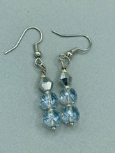 Load image into Gallery viewer, These earrings feature two shimmery iridescent glass beads with a single silver glass bead. Measurements: 1 1/2” in length