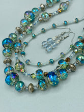 Load image into Gallery viewer, These earrings feature two shimmery iridescent glass beads with a single silver glass bead. Measurements: 1 1/2” in length