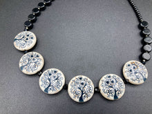 Load image into Gallery viewer, This eye-catching, sizable and conspicuous black stone beads create a powerful accent piece. Crafted of reconstituted quartzite lentil beads in a tree pattern, these beads measure approximately 24mm. To enhance their effect, a round necklace of black glass beads is included. Perfect for casual or formal wear, this necklace adds an elegant finish to any ensemble. Matching earrings feature white rose reconstituted quartzite beads, completing the set. Measurements: Necklace is 18 " in length