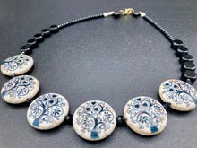 Load image into Gallery viewer, This eye-catching, sizable and conspicuous black stone beads create a powerful accent piece. Crafted of reconstituted quartzite lentil beads in a tree pattern, these beads measure approximately 24mm. To enhance their effect, a round necklace of black glass beads is included. Perfect for casual or formal wear, this necklace adds an elegant finish to any ensemble. Matching earrings feature white rose reconstituted quartzite beads, completing the set. Measurements: Necklace is 18 " in length