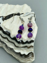Load image into Gallery viewer, These elegant, glass beaded earrings feature dainty light and dark purple hues, making them a great addition to any summer wardrobe. Perfect for hippie and nature-inspired looks, they are sure to accentuate any style. Measurements: 1 ” in length