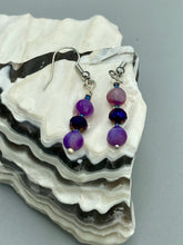 Load image into Gallery viewer, These elegant, glass beaded earrings feature dainty light and dark purple hues, making them a great addition to any summer wardrobe. Perfect for hippie and nature-inspired looks, they are sure to accentuate any style.  Measurements: 1 ” in length