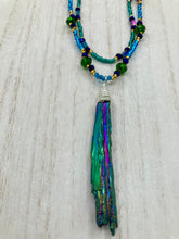 Load image into Gallery viewer, This Celestial and Galaxy Vibe Necklace features a 2 1/2" long Rainbow Kyanite Wired Stone pendant and two strands of multi-color glass beaded necklaces. The glass beads are an eclectic mix of sizes and shapes, including rectangular hematite beads, creating a shimmery, bold display of purples, blues, greens and golds. This necklace truly captures the essence of this celestial galaxy stone.Necklace is 15 1/2” in length can be adjusted to 18" in length