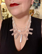 Load image into Gallery viewer, This impressive three-strand necklace is crafted from natural rose quartz stones and iridescent glass beads. The shortest strand is composed of petite round rose quartz beads, while the second strand contains an array of rectangular-shaped rose quartz and iridescent glass beads. The longest strand has long, vertical rectangular-shaped rose quartz beads, creating an elegant display across the chest. This necklace is an impressive, dynamic accessory. Necklace is 17: in length, can be adjusted to 19"