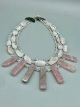 Load image into Gallery viewer, This impressive three-strand necklace is crafted from natural rose quartz stones and iridescent glass beads. The shortest strand is composed of petite round rose quartz beads, while the second strand contains an array of rectangular-shaped rose quartz and iridescent glass beads. The longest strand has long, vertical rectangular-shaped rose quartz beads, creating an elegant display across the chest. This necklace is an impressive, dynamic accessory. Necklace is 17: in length, can be adjusted to 19"