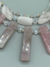 Load image into Gallery viewer, This impressive three-strand necklace is crafted from natural rose quartz stones and iridescent glass beads. The shortest strand is composed of petite round rose quartz beads, while the second strand contains an array of rectangular-shaped rose quartz and iridescent glass beads. The longest strand has long, vertical rectangular-shaped rose quartz beads, creating an elegant display across the chest. This necklace is an impressive, dynamic accessory. Necklace is 17: in length, can be adjusted to 19"