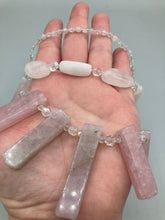 Load image into Gallery viewer, This impressive three-strand necklace is crafted from natural rose quartz stones and iridescent glass beads. The shortest strand is composed of petite round rose quartz beads, while the second strand contains an array of rectangular-shaped rose quartz and iridescent glass beads. The longest strand has long, vertical rectangular-shaped rose quartz beads, creating an elegant display across the chest. This necklace is an impressive, dynamic accessory. Necklace is 17: in length, can be adjusted to 19"