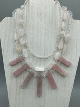 Load image into Gallery viewer, This impressive three-strand necklace is crafted from natural rose quartz stones and iridescent glass beads. The shortest strand is composed of petite round rose quartz beads, while the second strand contains an array of rectangular-shaped rose quartz and iridescent glass beads. The longest strand has long, vertical rectangular-shaped rose quartz beads, creating an elegant display across the chest. This necklace is an impressive, dynamic accessory. Necklace is 17: in length, can be adjusted to 19"